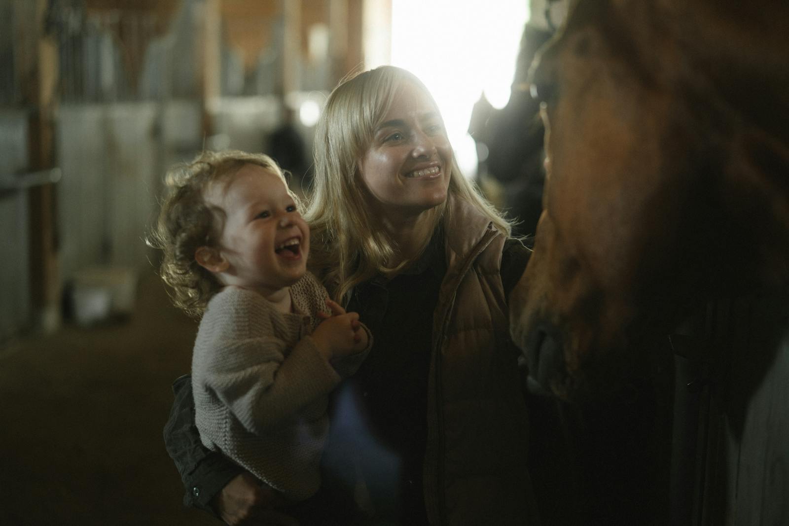 Child and parent smiling beside a horse